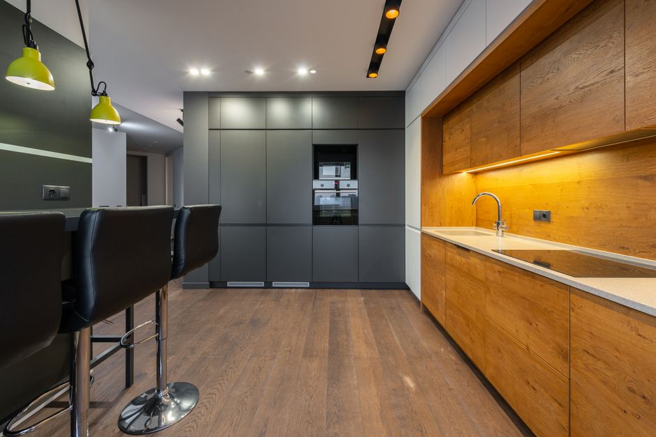 Spacious kitchen with modern wooden cabinets and sleek design lighting.