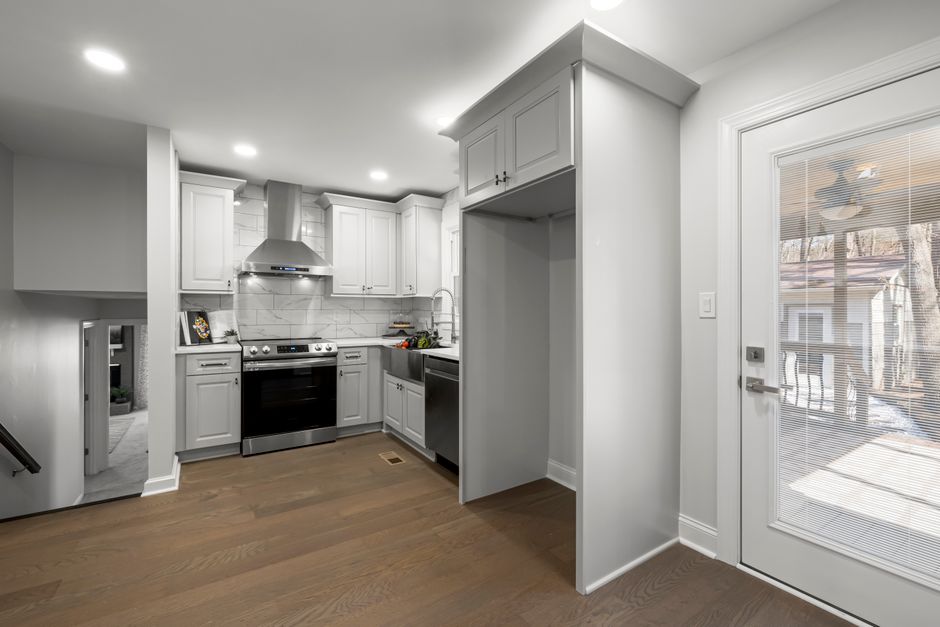 Bright minimalist kitchen with stainless steel appliances and wooden flooring.