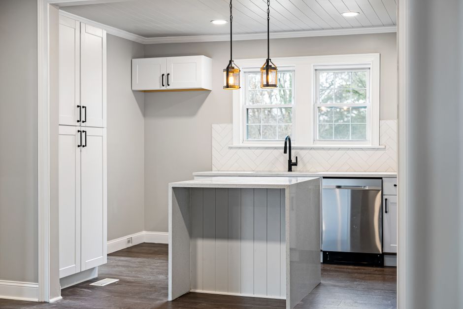A sleek, contemporary kitchen with modern white cabinets and island lighting.