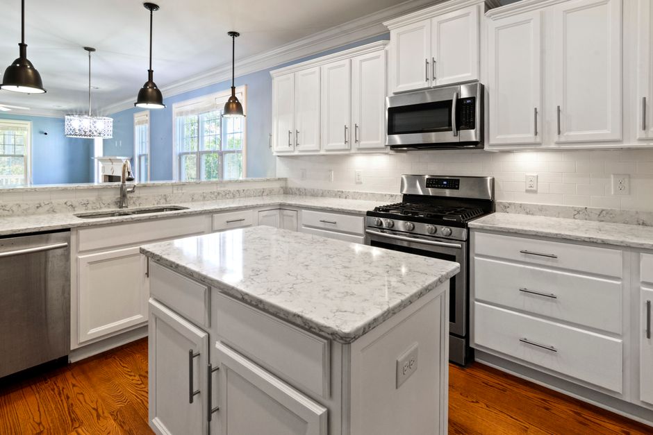 A bright, spacious kitchen with marble countertops, stainless steel appliances