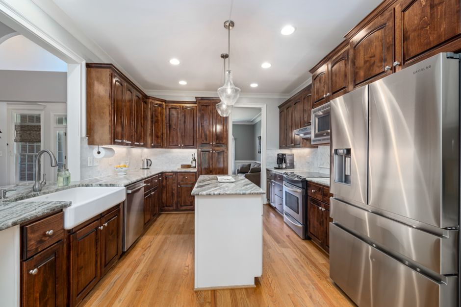 Spacious modern kitchen featuring wooden cabinets and stainless steel appliances with elegant lighting.