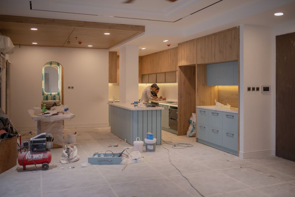 A modern kitchen undergoing renovation, featuring a worker, tools