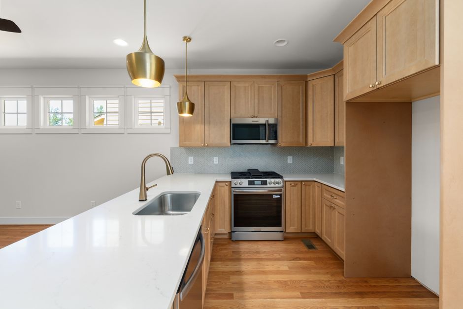 Spacious modern kitchen featuring wooden cabinets, stainless steel appliances, and stylish pendant lighting.