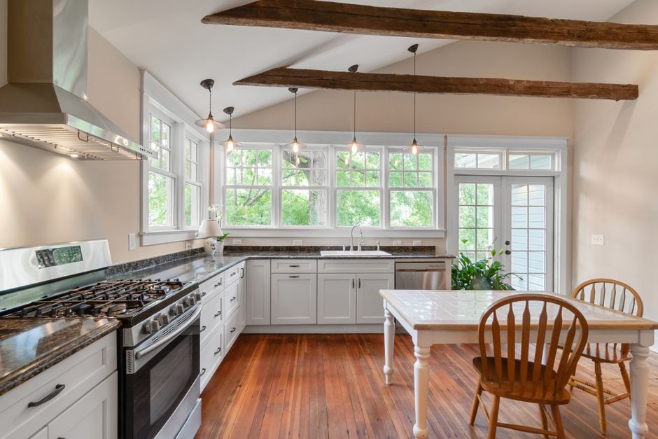 Bright kitchen interior featuring wooden beams, white cabinetry, and natural lighting.